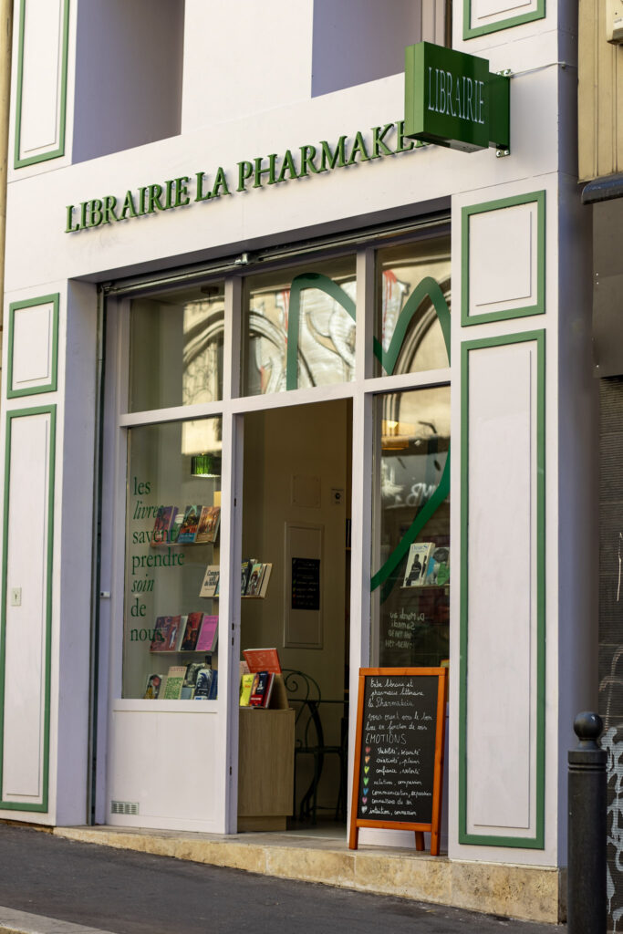 Photo de la devanture mauve avec les motifs et écritures verte de la librairie la pharmakeia,