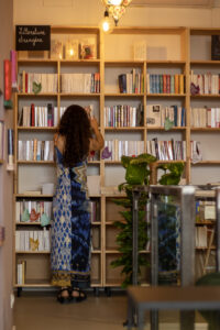 photo de grande biblothèque rempli de livre, un écriteau "littérature étrangère" avec Roxanne de dos rangeant les livres.