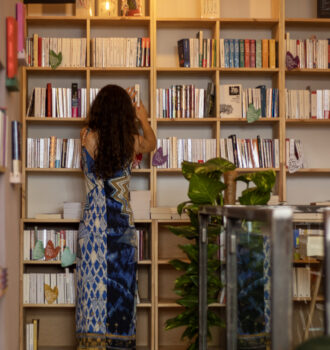 photo de grande biblothèque rempli de livre, un écriteau "littérature étrangère" avec Roxanne de dos rangeant les livres.