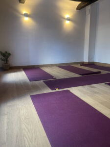 salle de cours de yoga avec des tapis violets poser sur le sol